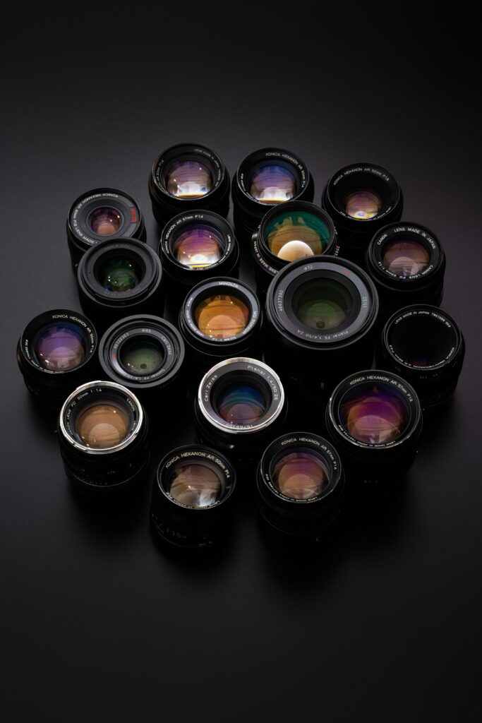 Diverse collection of camera lenses arranged on a sleek black surface.